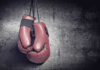 Red boxing gloves on a dark, textured surface.