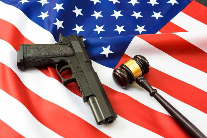 shutterstock_2214433687 Gun and gavel on a U.S. flag.
