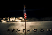 Pentagon Admits Alarming Troop Toll American flag above engraved Pentagon sign at night