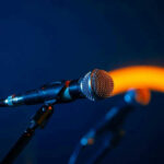 Fans Stunned: Music Superstar’s Disappearance Explained Close-up of a microphone on a stand, dark background.
