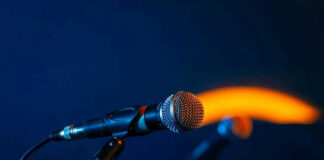 Close-up of a microphone on a stand, dark background.