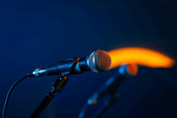 Close-up of a microphone on a stand, dark background.