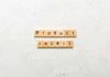 Wooden letter tiles forming words on a white textured surface