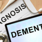 Medical diagnosis paperwork and a tablet displaying the word Dementia