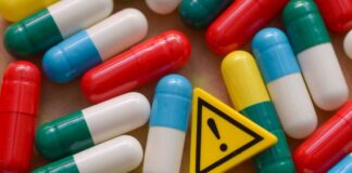 Colorful capsules scattered around a yellow warning sign