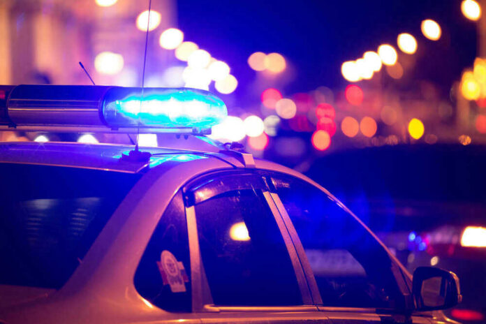shutterstock_448997113 Police car with blue lights flashing at night.