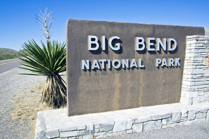 Big,Bend,National,Park,-,Welcome,Sign Group of people walking by a border fence.