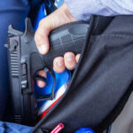 School Bloodbath Stuns Nation A hand holding a gun inside a backpack