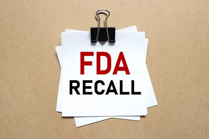 Fda,Recall.,The,Paper,Is,Clamped,With,A,Clerical,Clip. A notice labeled 'FDA RECALL' clipped to white papers on a brown background