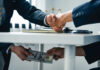Businessmen handshake while cash is passed under the table