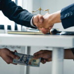 Businessmen handshake while cash is passed under the table