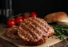 Burger Wars: Grass-Fed Gambit Announced Grilled burger patties on parchment with rosemary and tomatoes