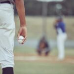 A young baseball player holding a baseball while preparing to pitch
