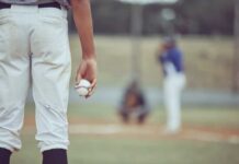 A young baseball player holding a baseball while preparing to pitch