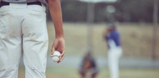 A young baseball player holding a baseball while preparing to pitch