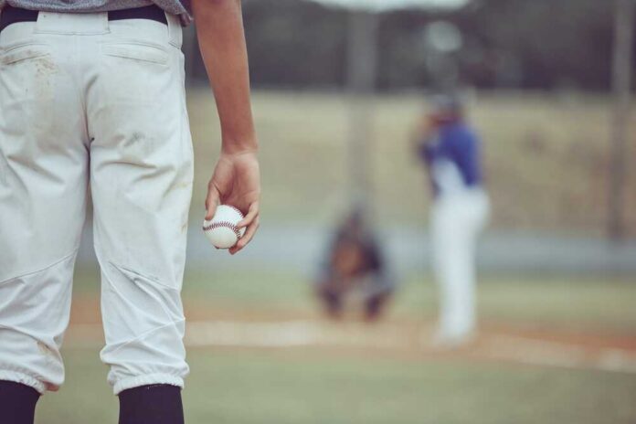 Baseball,Player,Holding,Ball,During,A,Game,On,The,Field. A young baseball player holding a baseball while preparing to pitch
