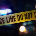 Police tape with blurred emergency lights in the background