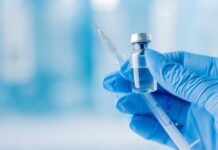A gloved hand holding a syringe and a vial of liquid