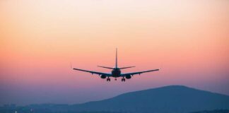 An airplane approaching for landing against a colorful sunset sky