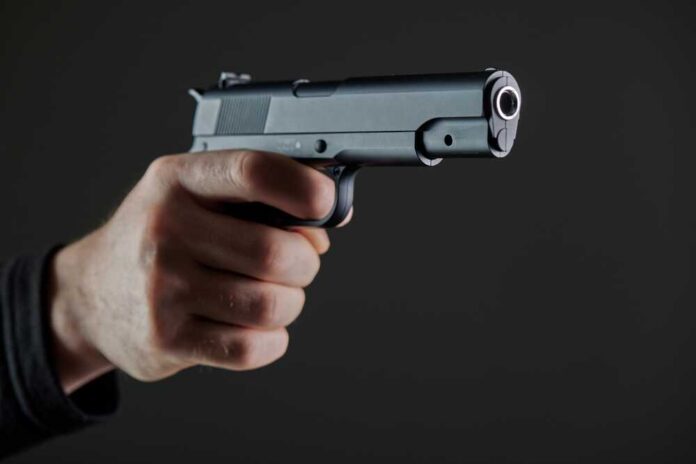 Male,Hand,Holding,A,Gun,On,Black,Background,.,A Hand holding a semi-automatic pistol pointed forward