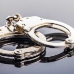 Close-up of metallic handcuffs on a reflective surface