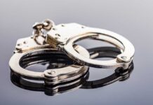 Close-up of metallic handcuffs on a reflective surface