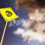 Grim Mine Find – 14 Dead Yellow warning sign with skull symbol under dramatic cloudy sky