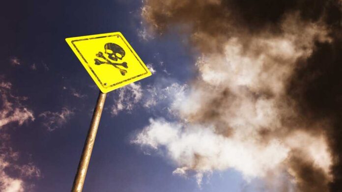 Road,Sign,Against,Blue,Sky.,Skull,And,Crossbones.,Danger,Of Yellow skull and crossbones warning sign against smoky sky