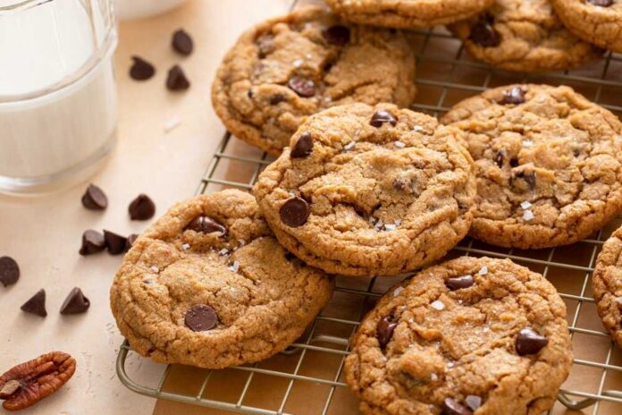 Chocolate,Chip,Cookies,With,Pecan,Nuts,,Freshly,Baked,Cookies,On Chocolate chip cookies cooling on a wire rack beside a glass of milk