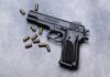 Hero Gunshots Changed Everything Black semi-automatic pistol with scattered brass cartridges on a gray surface