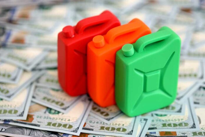 Gasoline,Canister,Lies,On,Big,Amount,Of,Dollar,Bills.,Concept Three colorful plastic containers on a background of hundred dollar bills