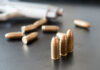 Loaded Mag Found — Trump Visit Looms Close-up of bullets on a dark surface with a handgun in the background