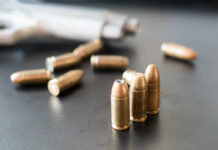 Loaded Mag Found β Trump Visit Looms Close-up of bullets on a dark surface with a handgun in the background