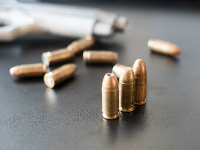 11mm,Bullets,And,Short,Gun,On,Black,Background.,(selective,Focus) Close-up of bullets on a dark surface with a handgun in the background
