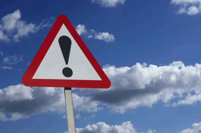 shutterstock_539658352-1 Warning sign with exclamation mark against sky