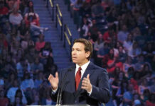 DeSantis Scores Another Crime Record-Breaker Ron DeSantis speaking at a podium before a large audience