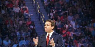 Ron DeSantis speaking at a podium before a large audience