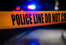 Another School Horror: Teacher Gunned Down Police tape with flashing lights in the background.