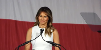 Melania Trump speaking at a podium with microphones