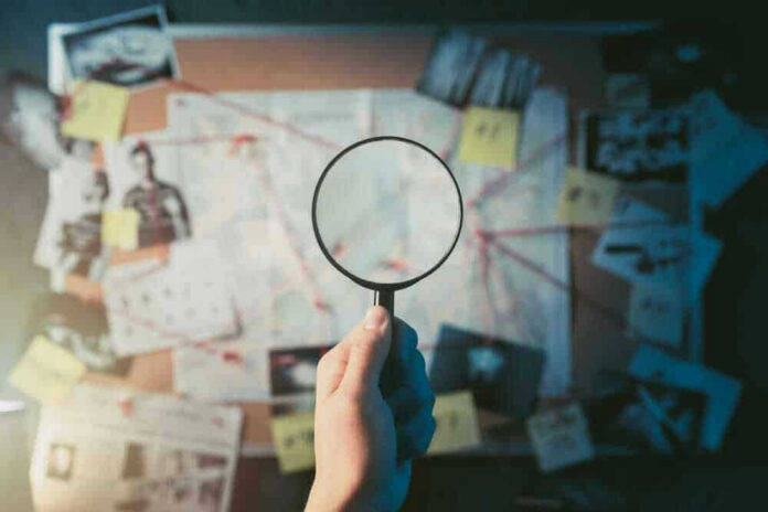 shutterstock_1192132651-1 Magnifying glass over investigation board with photos and strings.