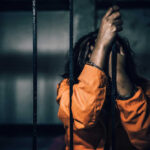 Florida’s Double Execution Day Arrives Person in orange prison uniform behind bars, head down.