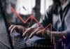 VIDEO: Worst Since 2014 – Brace For Pain Person typing on a laptop with a declining stock market graph overlay