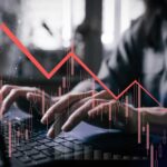 VIDEO: Worst Since 2014 – Brace For Pain Person typing on a laptop with a declining stock market graph overlay