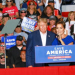 Trump’s Makes His Move: Paxton Over Cornyn Donald Trump at a rally with a woman speaking at the podium; Alexandros Papadiamantis, Margarita Stolbizer, and David Lowy are present in the crowd
