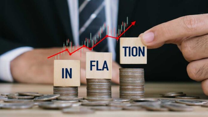 Hand,Putting,Inflation,Word,On,Wooden,Cube,On,Stack,Coins.world Blocks spelling 'INFLATION' placed on stacks of coins with a rising graph in the background