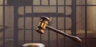 judge's gavel hovering above sound block in front of jail bars