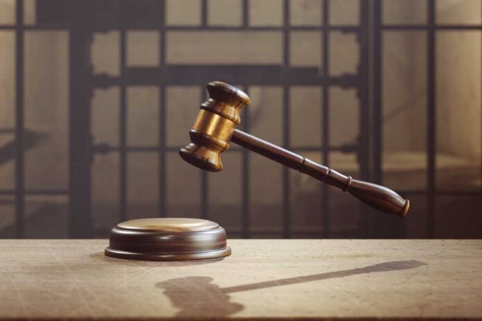 judge's gavel hovering above sound block in front of jail bars