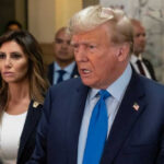 Donald Trump speaking in a hallway with aides around him