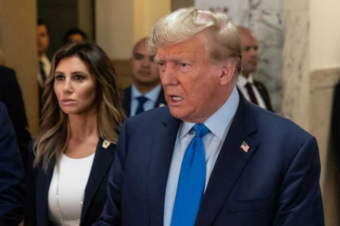 Donald Trump speaking in a hallway with aides around him