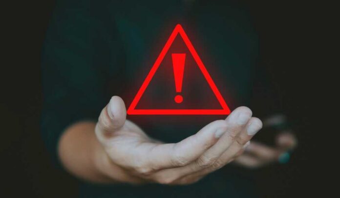 Alert,Alarm,Warning,Sign,On,Hand,,Concept,Of,Emergency,Caution A hand holding a red warning triangle with an exclamation mark